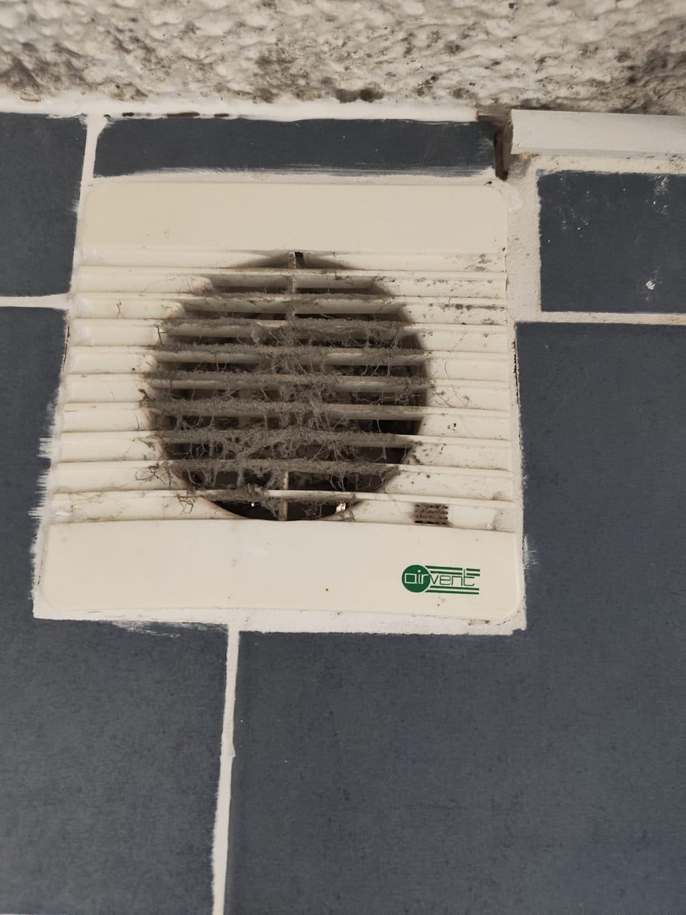 Extractor fan grille clogged with dust and fibre, restricting airflow