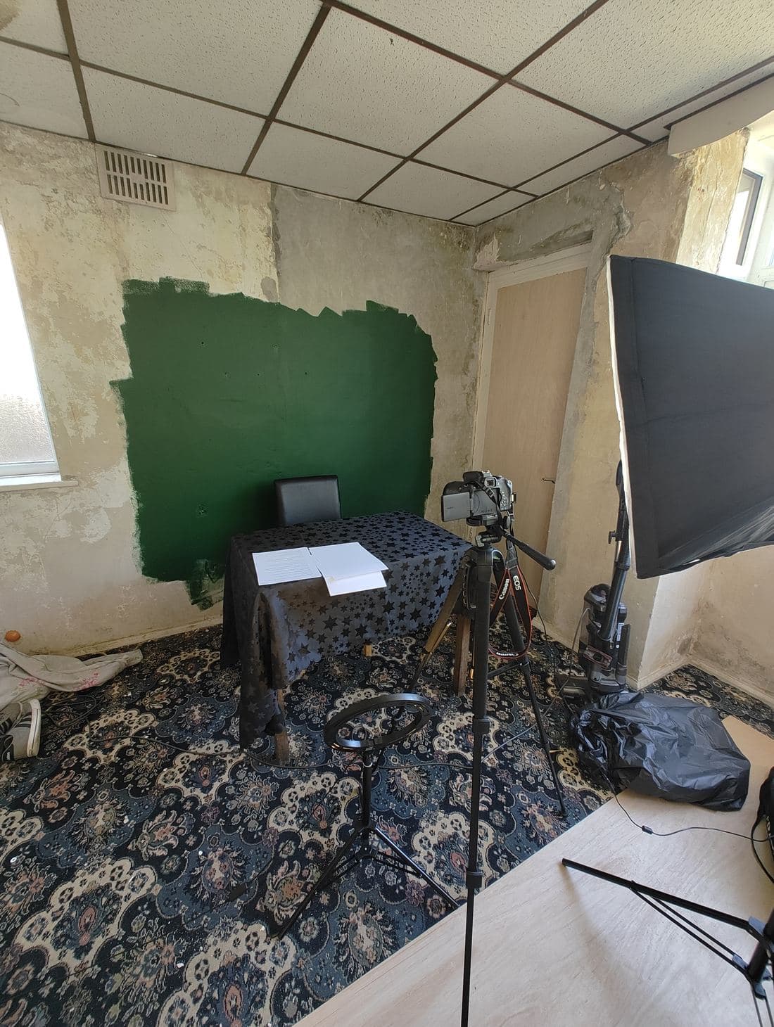 The podcast studio set up, with a hand-painted green screen, camera, and lighting rig